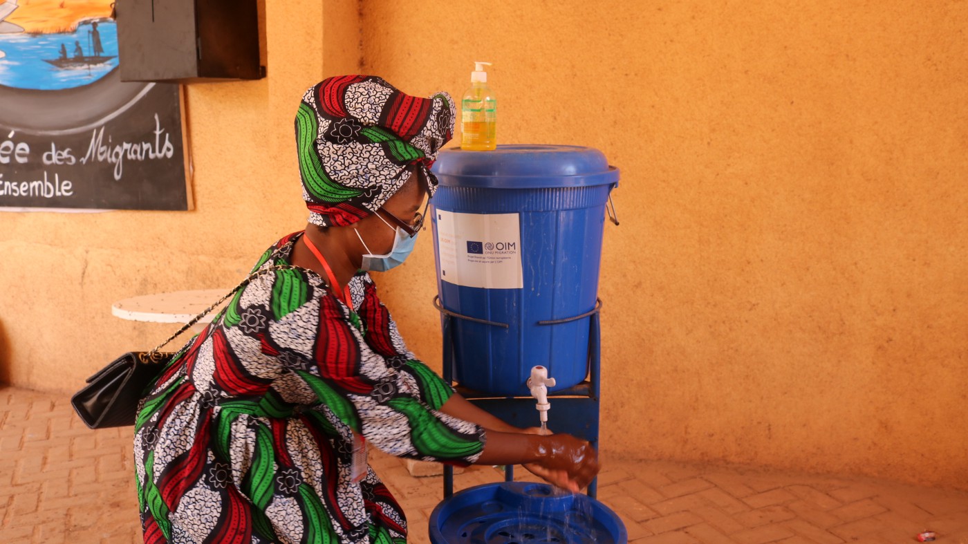 Woman wearing protective mouth mask washes her hands at Ouagadougou transit center, Burkina Faso.  ©IOM